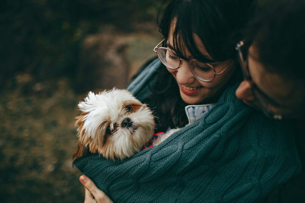 pexels-photo-1378849-1378849 A woman lovingly cuddles her Shih Tzu puppy, wrapped in a warm blanket outdoors.
